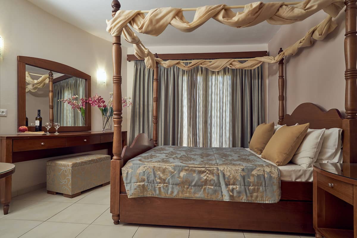 A four-poster bed with a canopy, a wooden nightstand, a bench, and a mirror above the dresser.