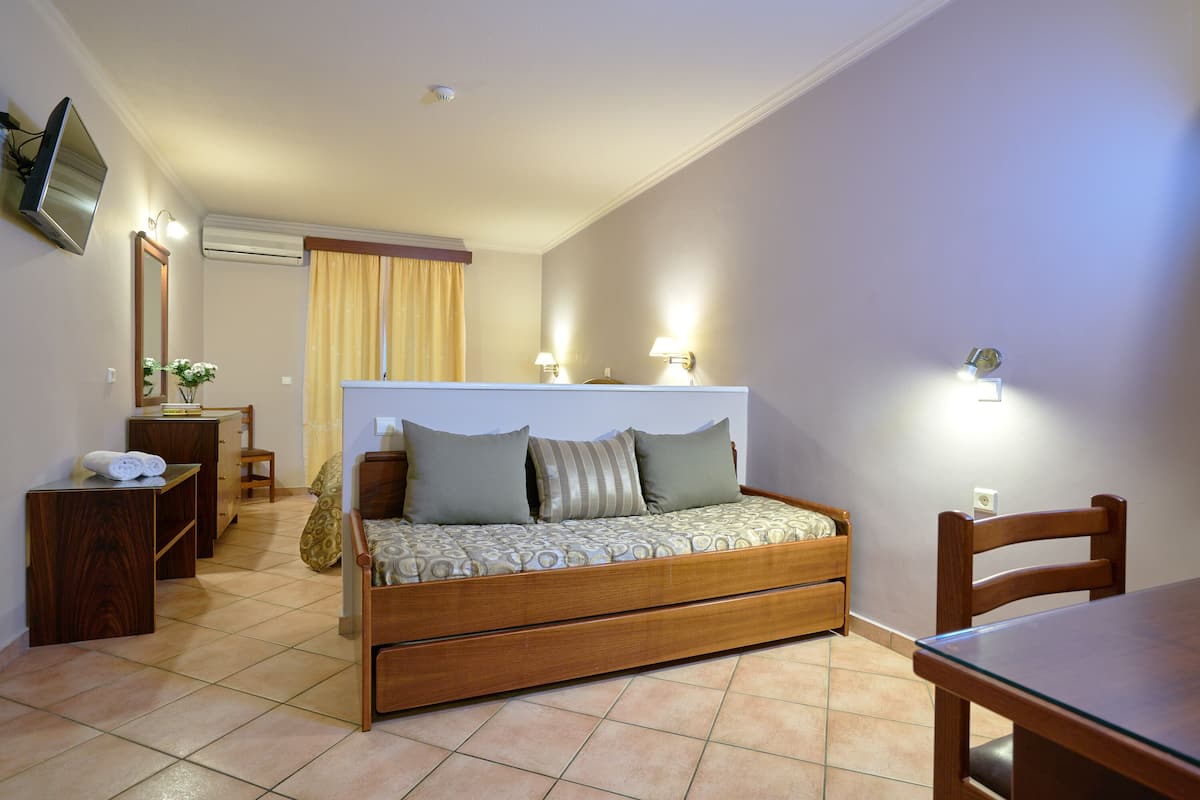 A bedroom with a bed, a desk, a chair, and a TV mounted on the wall.