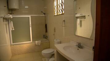 Een badkamer met douche, toilet, wastafel en spiegel.