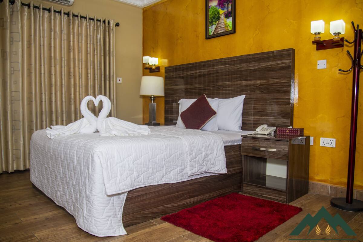 Ein Hotelzimmer mit einem großen Bett, einem roten Teppich, einem Holz-Kopfteil und einem Bild an der Wand.