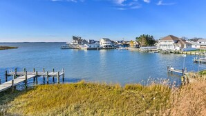 A waterfront property with dock access, houses, and a grassy foreground. - Upscale, stylish 3 bedroom condo with free WiFi, and outdoor pool, and a breathtaking view of the bay located in midtown and only two blocks from the beach! (Ocean City)