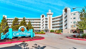 A hotel entrance with a sign reading "Captiva Bay," featuring a large building with multiple balconies and a central tower. - Upscale, stylish 3 bedroom condo with free WiFi, and outdoor pool, and a breathtaking view of the bay located in midtown and only two blocks from the beach! (Ocean City)
