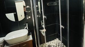 A modern bathroom with a glass-enclosed shower, a sink, and a mirror. - Karibu Guesthouse (Cape Town)