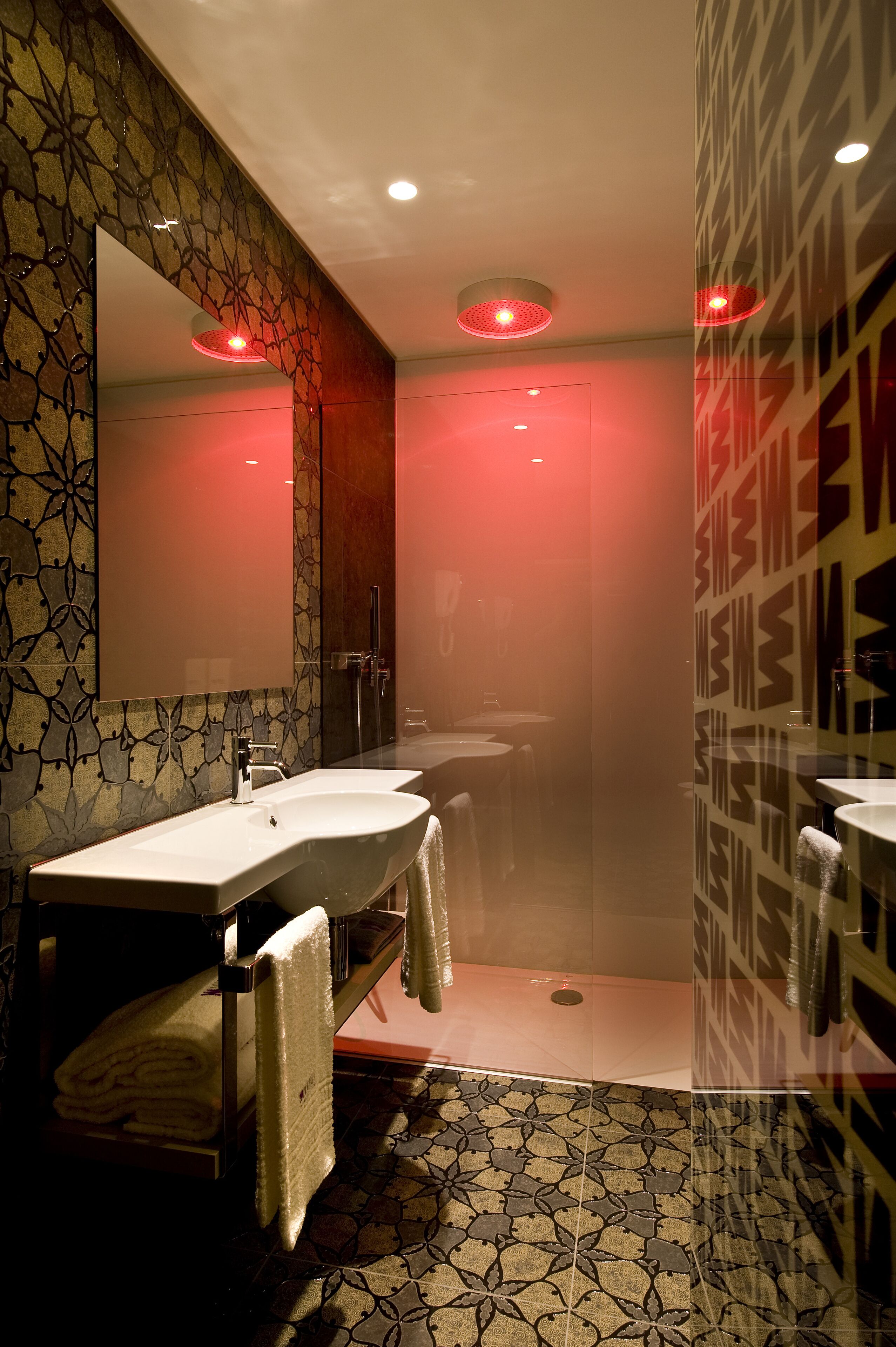 A modern bathroom with two sinks, a large mirror, and a shower area.