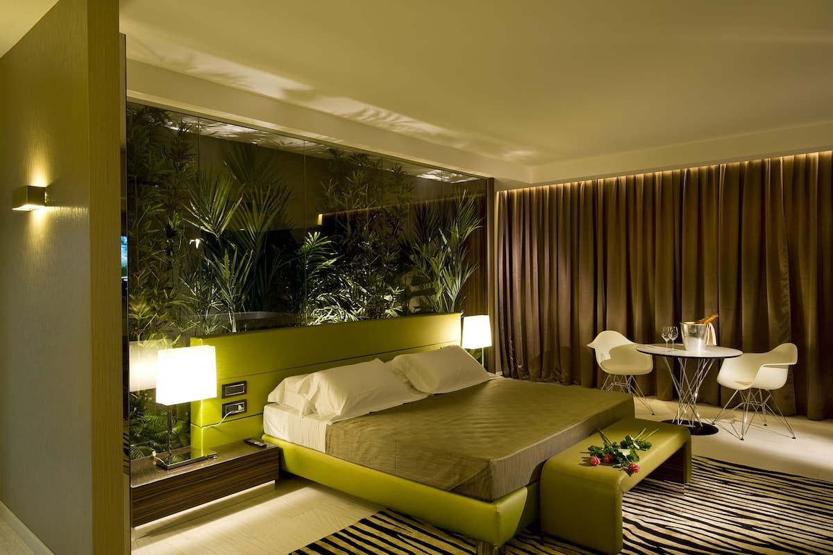 A hotel room with a bed, bedside table, lamp, and a small table with chairs.