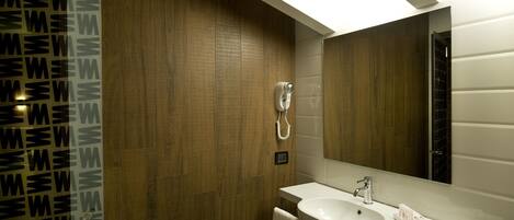 A modern bathroom with a wooden wall, a white sink, and a large mirror.