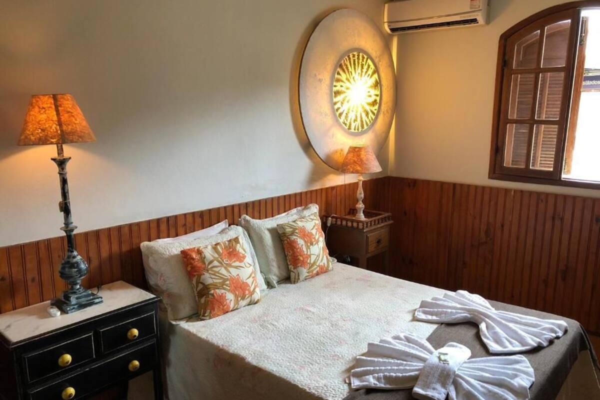 A neatly made bed with floral pillows, a bedside lamp, and a wall-mounted light fixture.