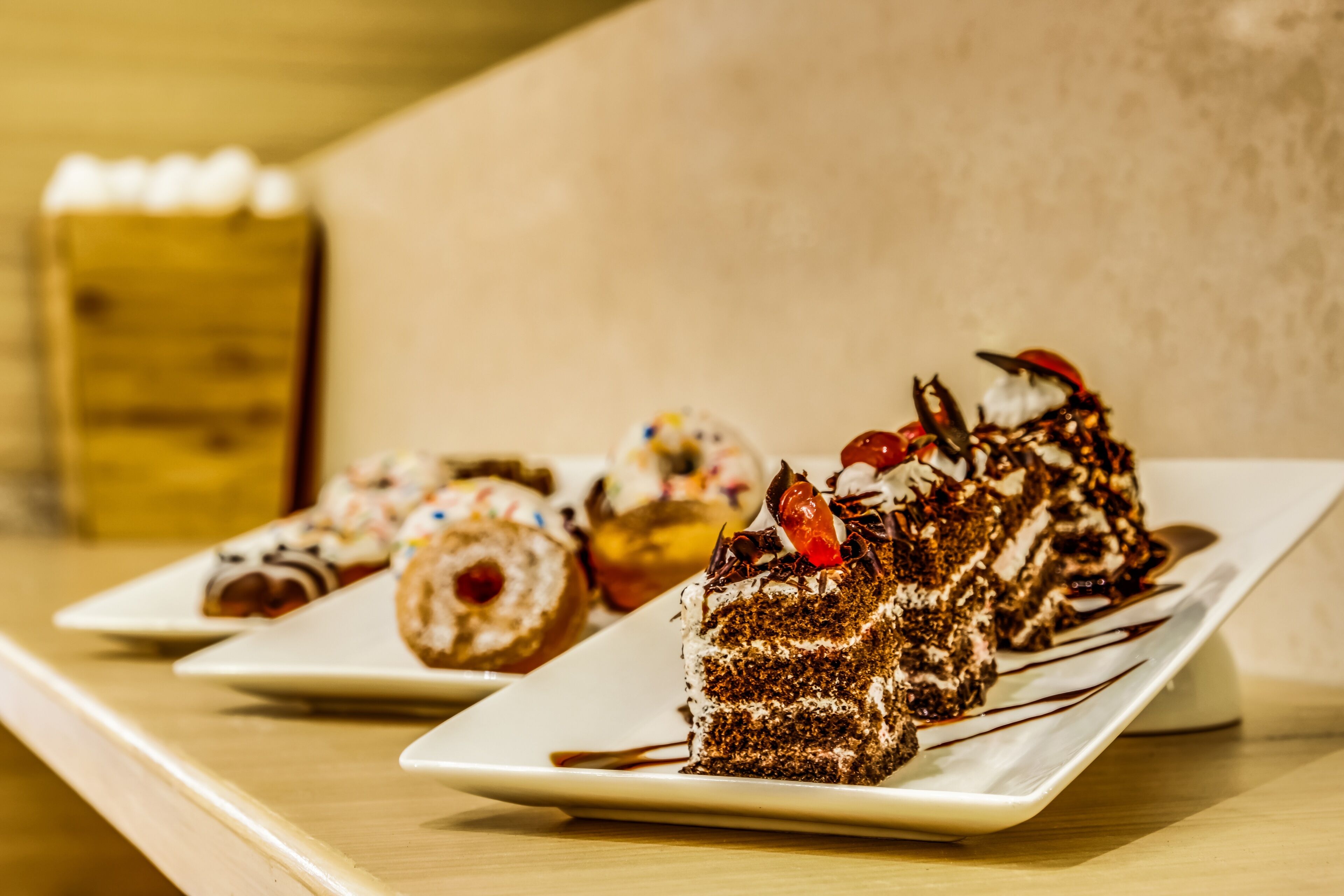 Una bandeja de postres con diversos pasteles y dulces sobre platos blancos.