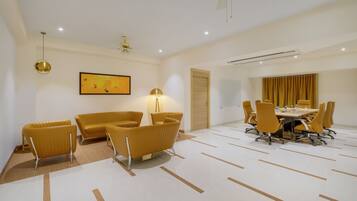 A modern conference room with a round table, yellow chairs, and a large painting on the wall.