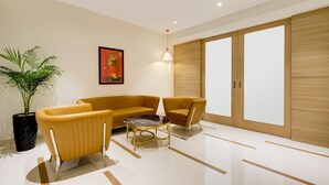 Una sala moderna con un sofá, un sillón y una mesa de centro. Hay una planta en maceta y un cuadro en la pared.