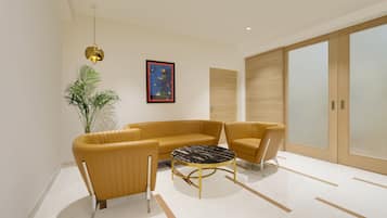 Een moderne woonkamer met een hoekbank, een rond bijzettafeltje en een kamerplant.