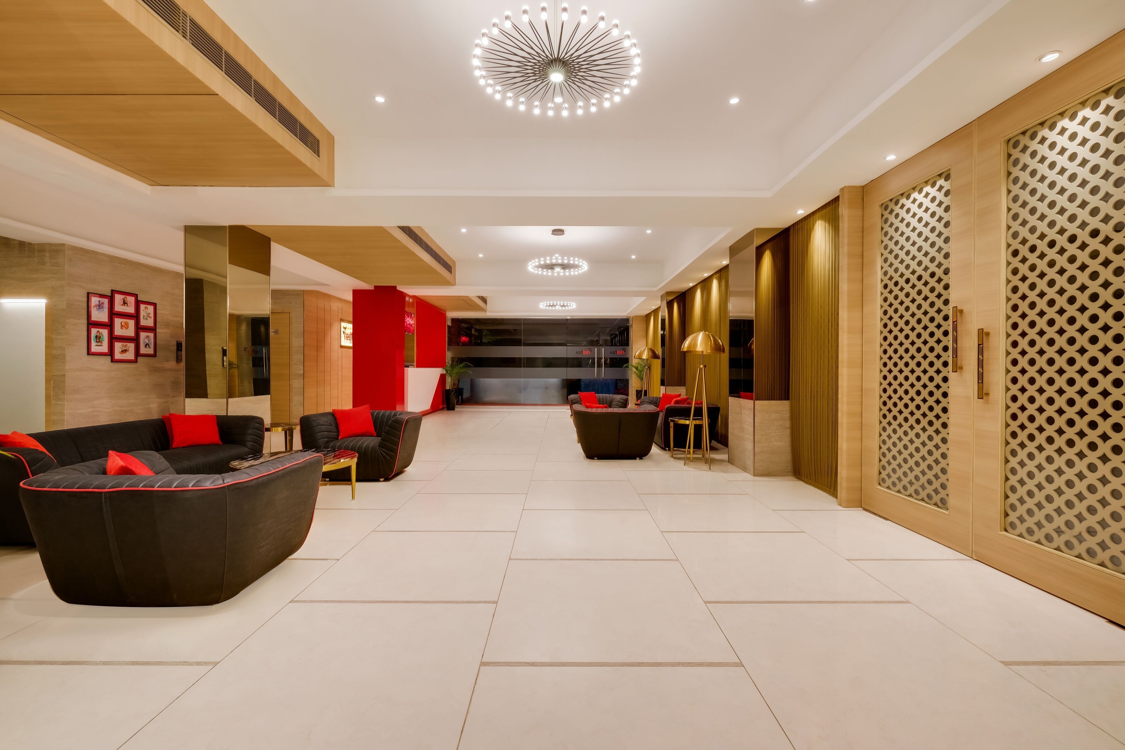A modern hotel lobby with a reception desk, seating area, and a staircase leading to an upper floor.