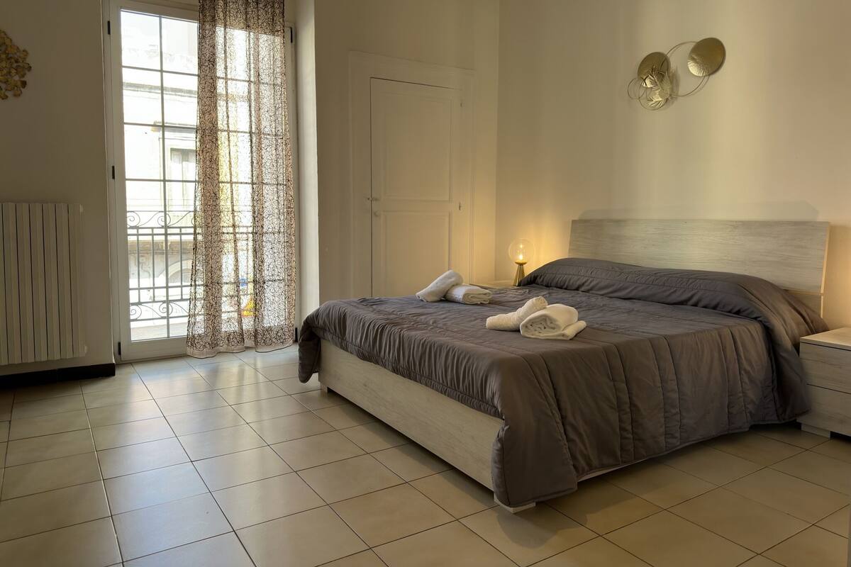 A bedroom with a bed, a nightstand, a lamp, and a door.
