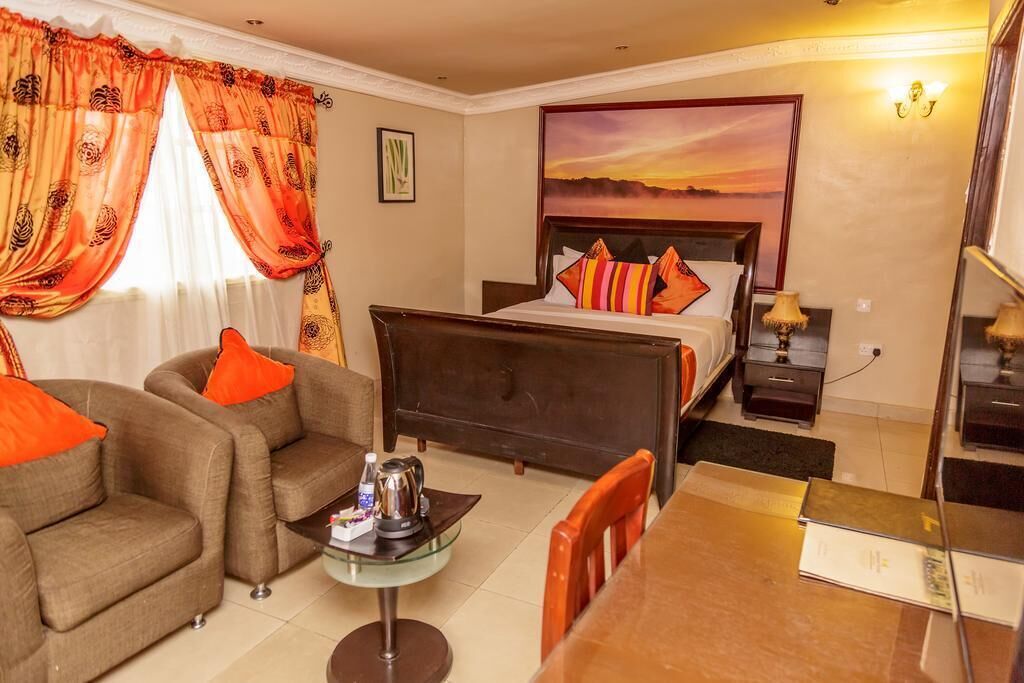 A hotel room with a bed, a sofa, a coffee table, and a desk.