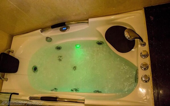 Une baignoire avec un éclairage vert, un siège noir et un robinet.