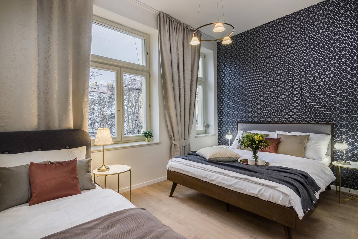 Ein modernes Schlafzimmer mit einem großen Bett, einem kleineren Bett und einem Fenster mit Vorhängen.