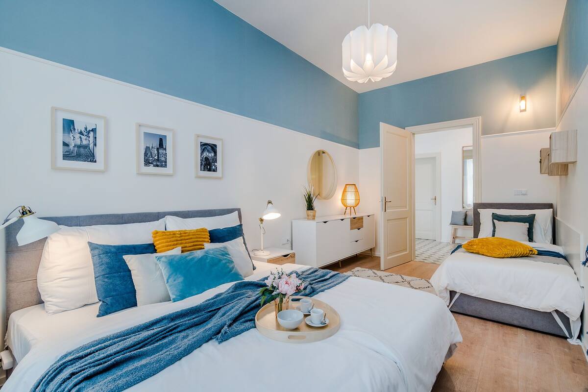 Ein modernes Schlafzimmer mit einem großen Bett, zwei Einzelbetten, einer Kommode und einem Spiegel.