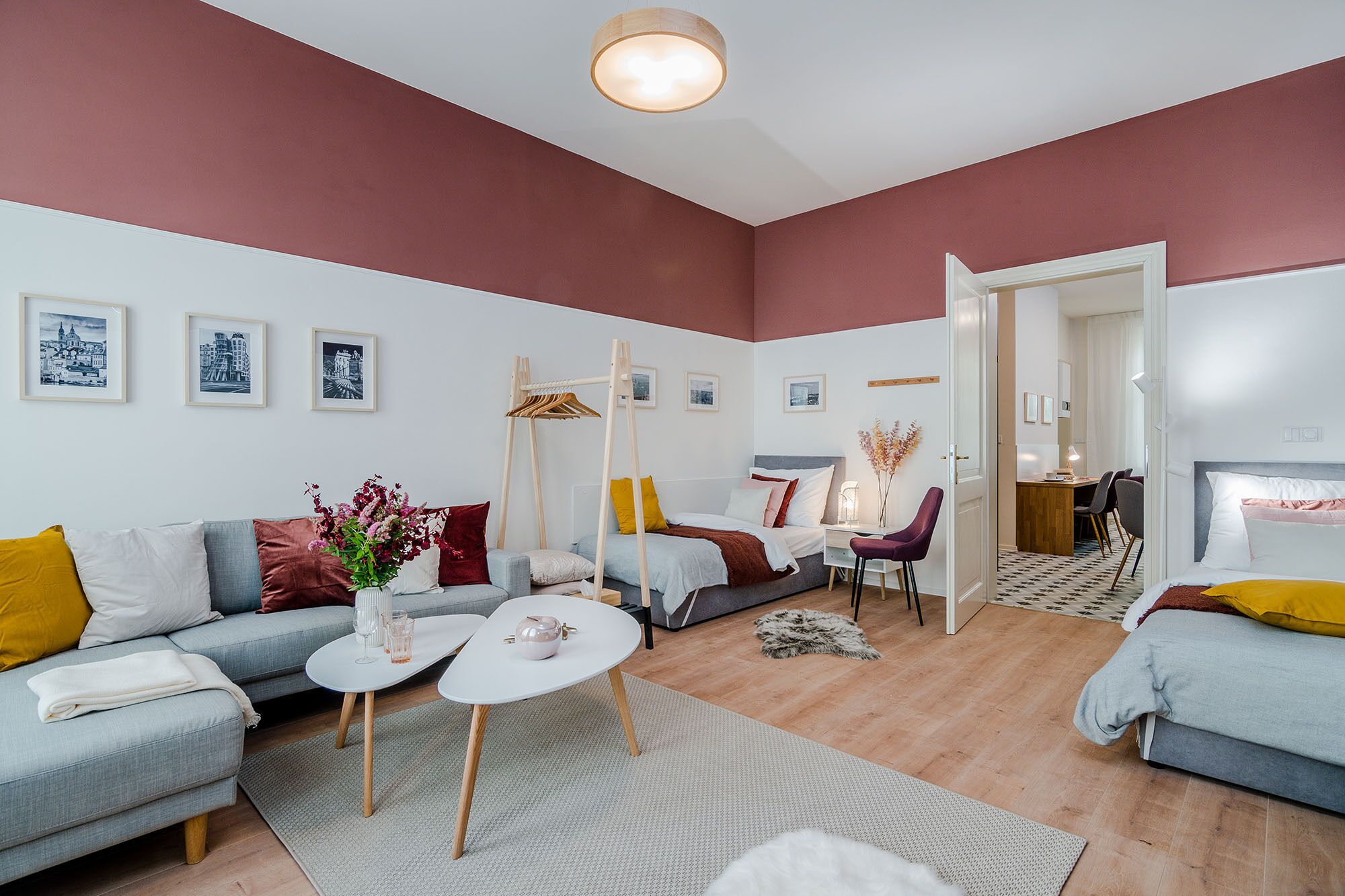 A modern living room with a grey sofa, a white coffee table, and a dining area with a wooden table and chairs.