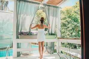 A person standing on a wooden deck with a view of a swimming pool and greenery. - Eili Suites (Ramot)