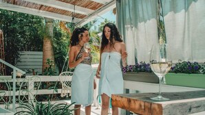 Two people standing on a wooden deck with a glass of wine on a table. - Eili Suites (Ramot)