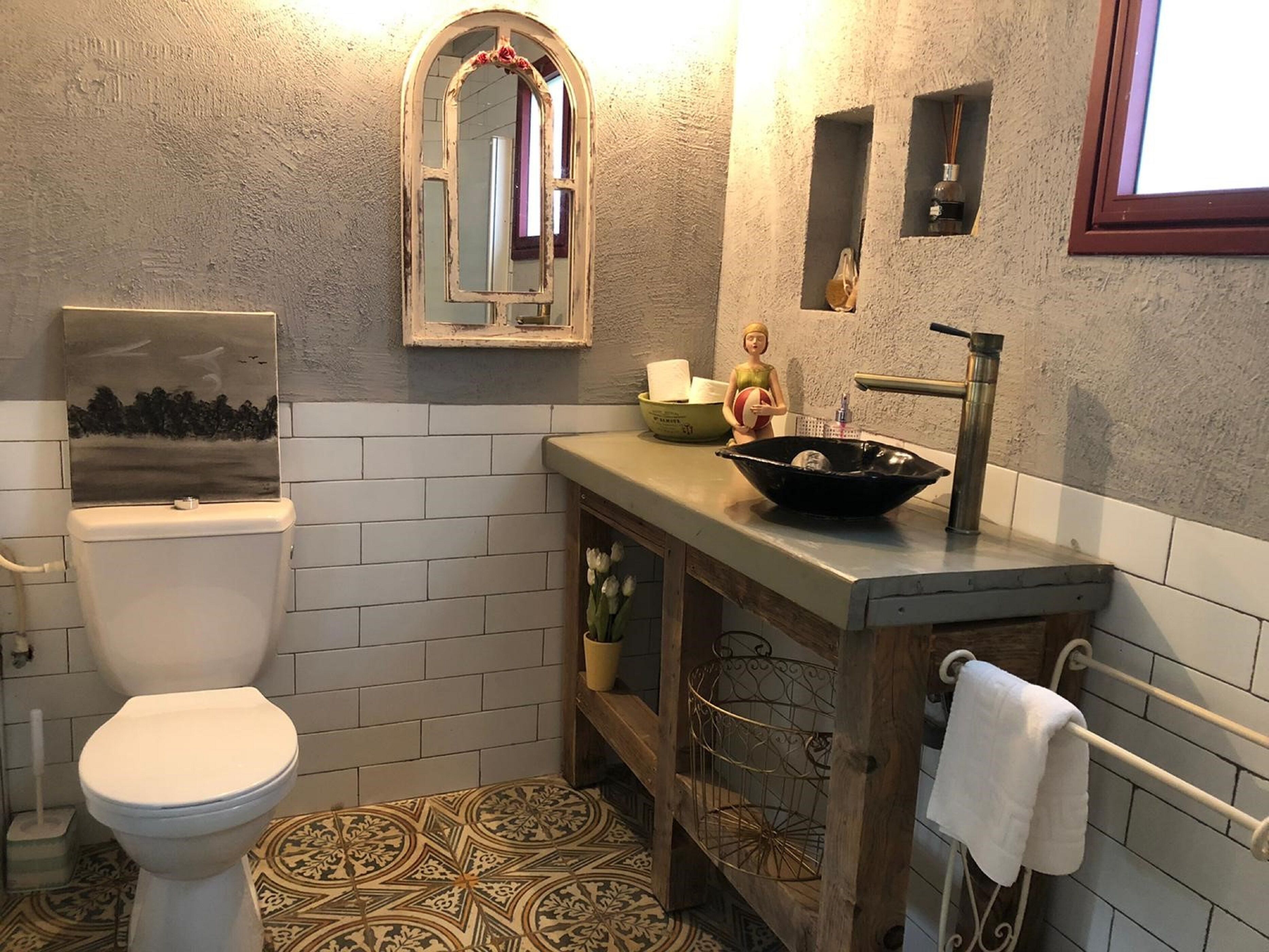 Ein Badezimmer mit Toilette, Waschbecken und einem dekorativen Spiegel.
