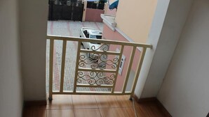 Un balcone con ringhiera in metallo, pavimento piastrellato e vista su un'auto parcheggiata e un edificio sullo sfondo.