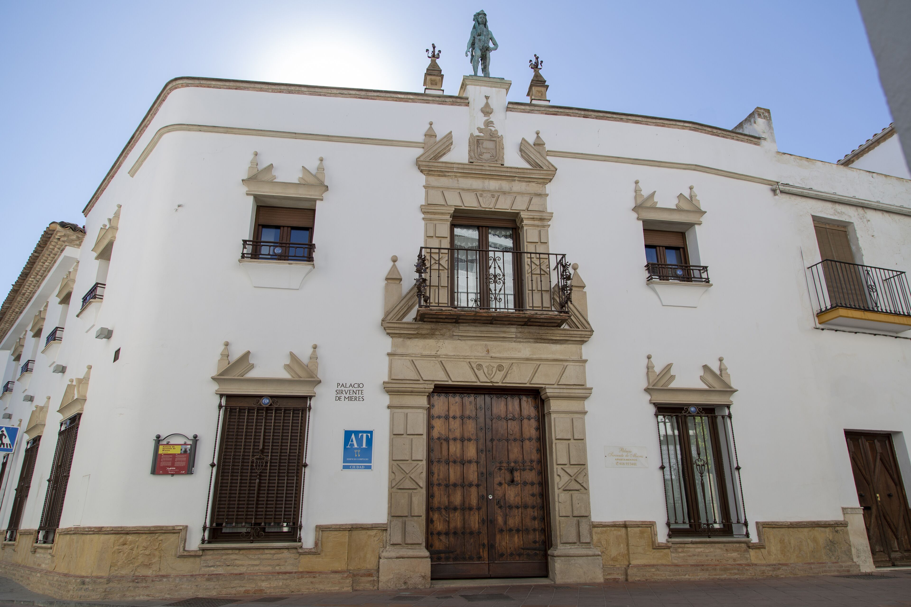 A building with a central entrance, two small windows on either side, and a balcony with a railing.