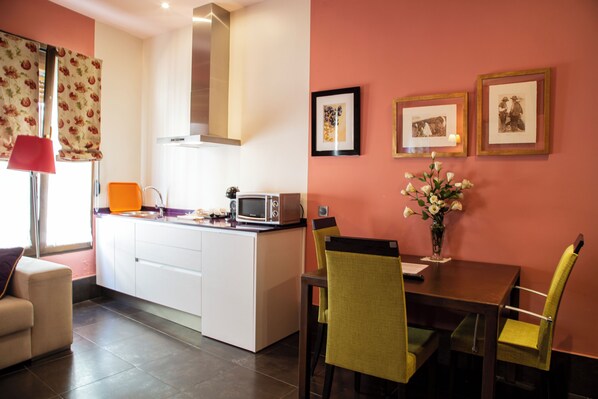 A compact kitchen with a microwave, a small island, and a dining area with chairs and a table. - Palacio Sirvente de Mieres (Andujar)