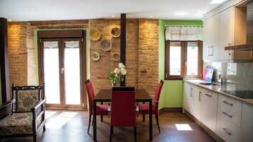 Un comedor con una mesa y sillas de madera, un florero con flores y una pared de piedra.