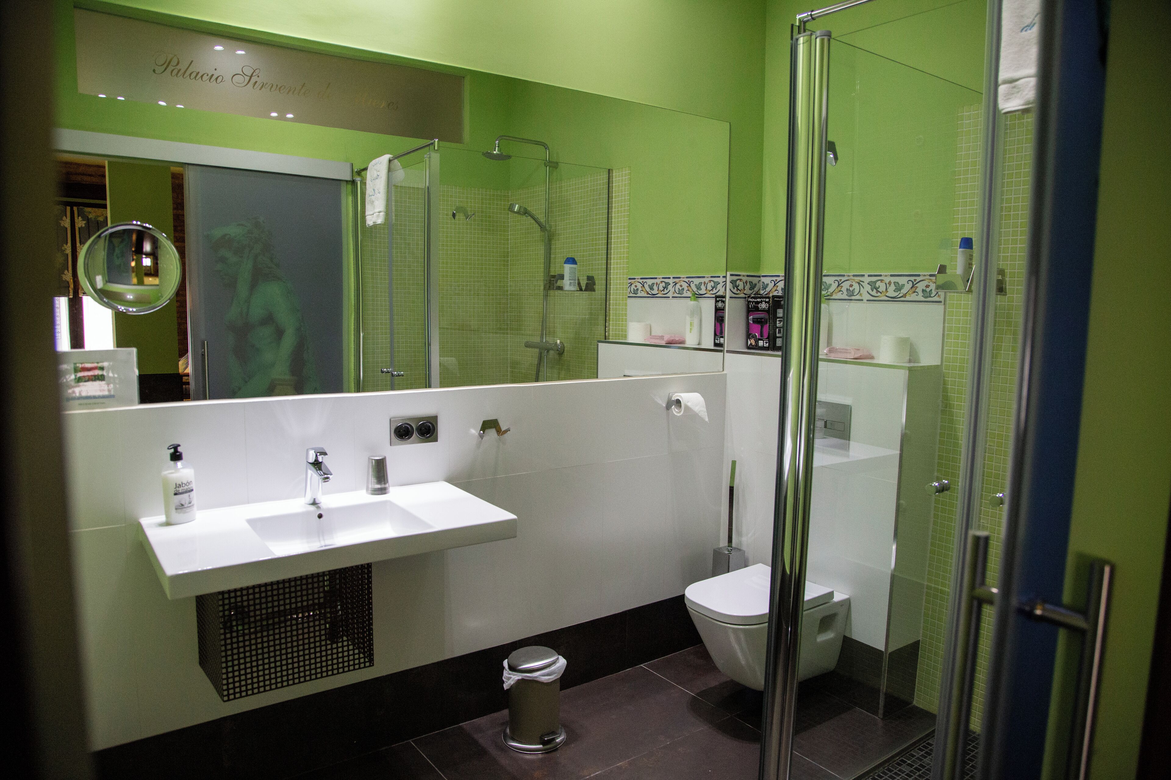 A modern bathroom with a glass-enclosed shower, a white sink, and a toilet.