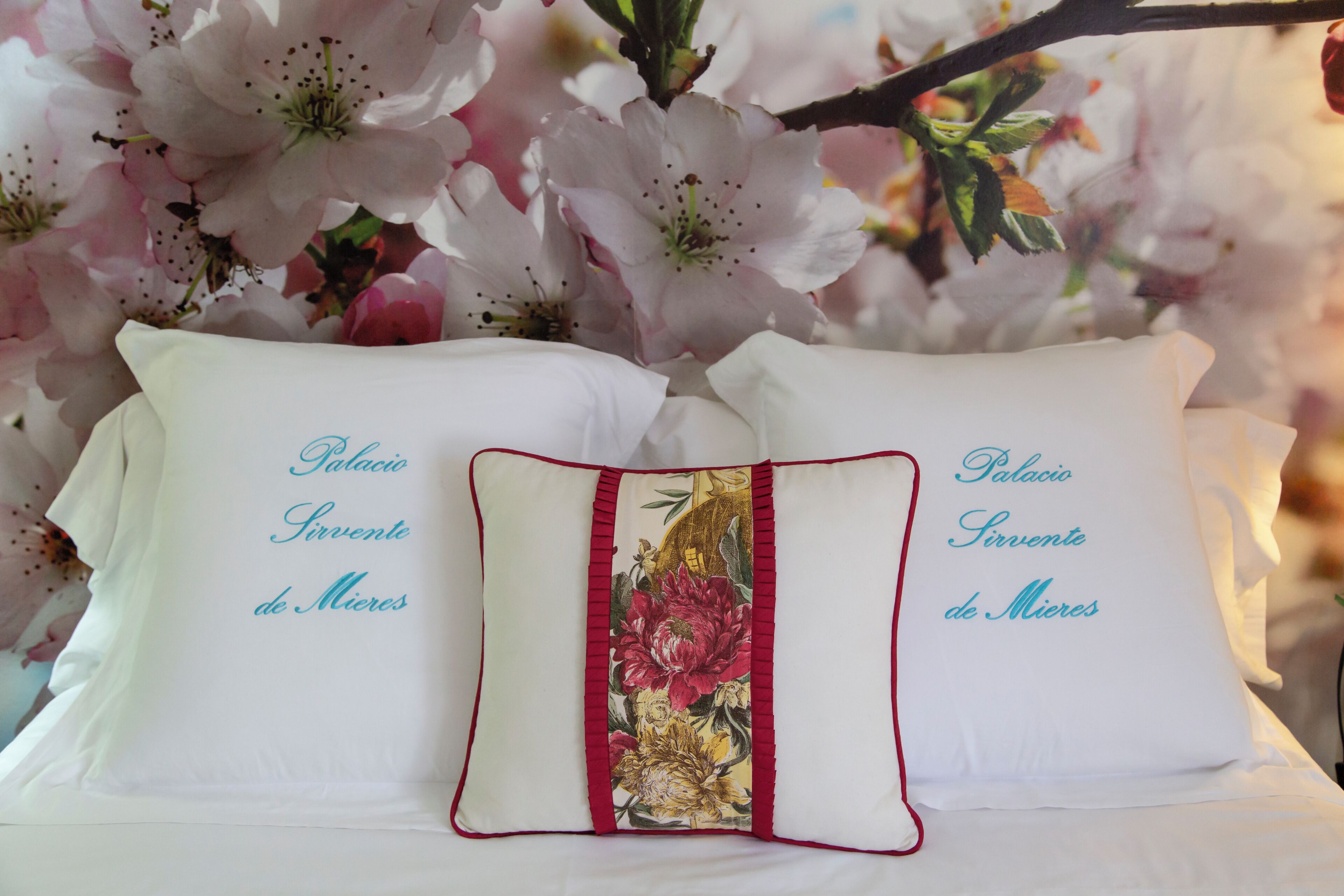 Two pillows with text and a central decorative pillow with floral embroidery.