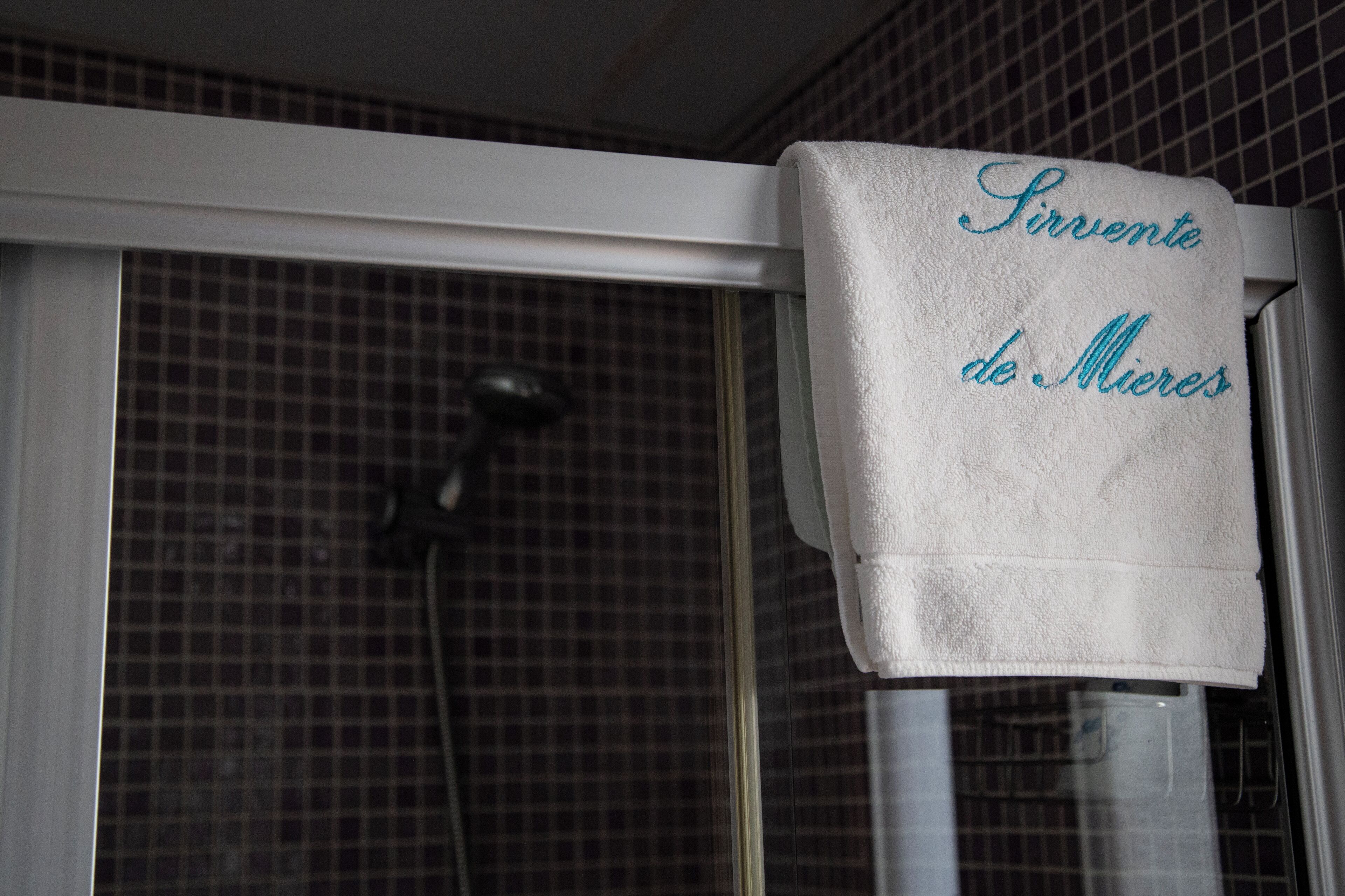 A bathroom with a shower and a towel hanging on the wall with text.