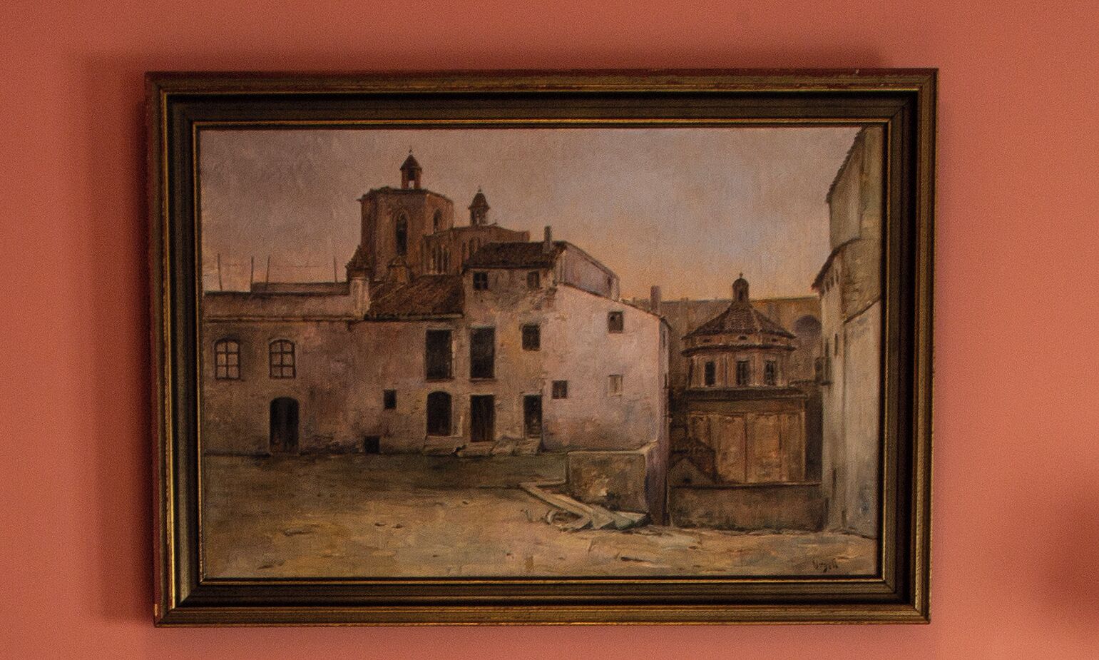 A framed painting of a building with multiple windows and a central tower.