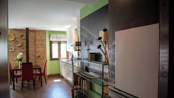 Una cocina con comedor, que presenta una pared de ladrillo, armarios verdes y una estantería.