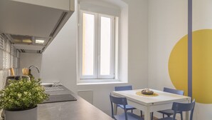 A modern kitchen with a window, white cabinets, and a dining area with blue chairs.