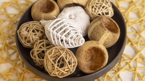 A bowl containing various woven items and gourds.
