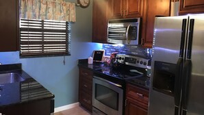 A kitchen with wooden cabinets, a stainless steel refrigerator, a microwave, an oven, and a sink.