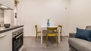 Une cuisine compacte comprenant une table et des chaises, un canapé et une petite plante décorative.