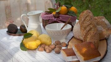 Una mesa con pan, nueces, limones y una jarrón.