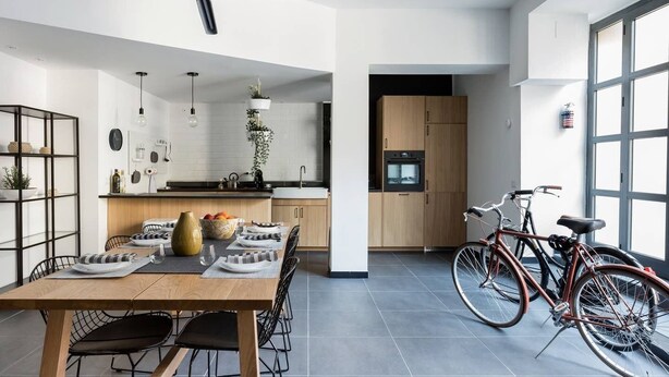 Una cocina moderna con comedor, una bicicleta y un amplio ventanal.