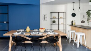 Una cocina moderna con una mesa de madera, sillas de alambre negras y una pared azul de acento.