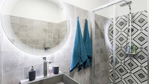 Un baño moderno con un espejo grande, una ducha y un lavabo.