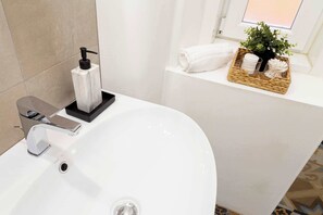 A bathroom with a white sink, chrome faucet, and a bottle of soap. There is a window with a view, a towel, and a basket with toiletries. - Elegant apartment★near the station★Gold★Free Wifi (Trieste)