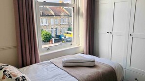 Un dormitorio con cama, ventana con cortinas y armario.