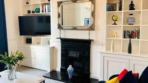 Una sala de estar con chimenea, un espejo grande y una televisión.