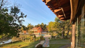 A garden pathway leading to a building with a red roof, surrounded by greenery and a clear sky. - SÍTIO DO IPÊ, please contact us before booking!!! (Residencial são vicente)