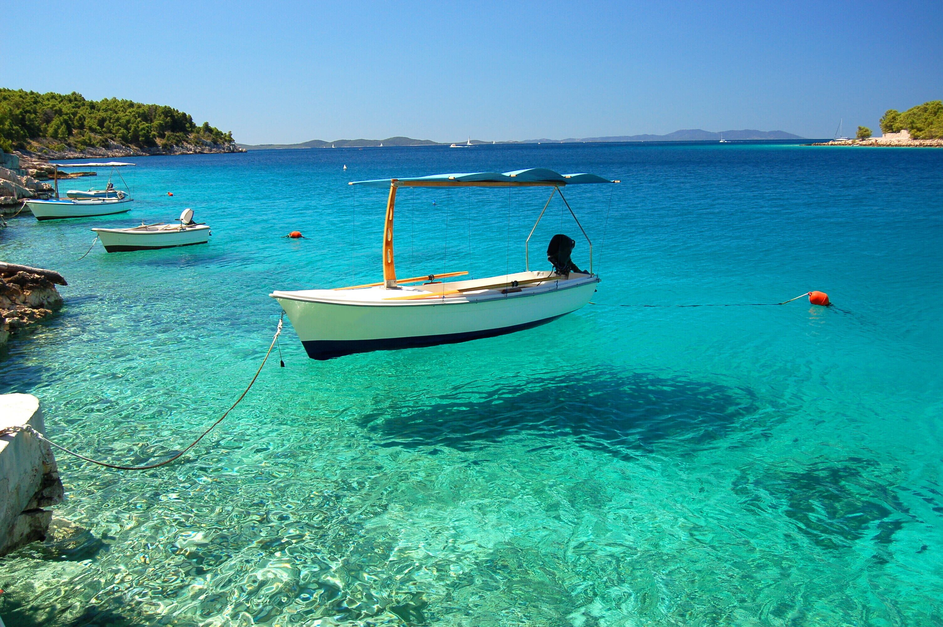 A clear blue sea with boats anchored near the shore.
