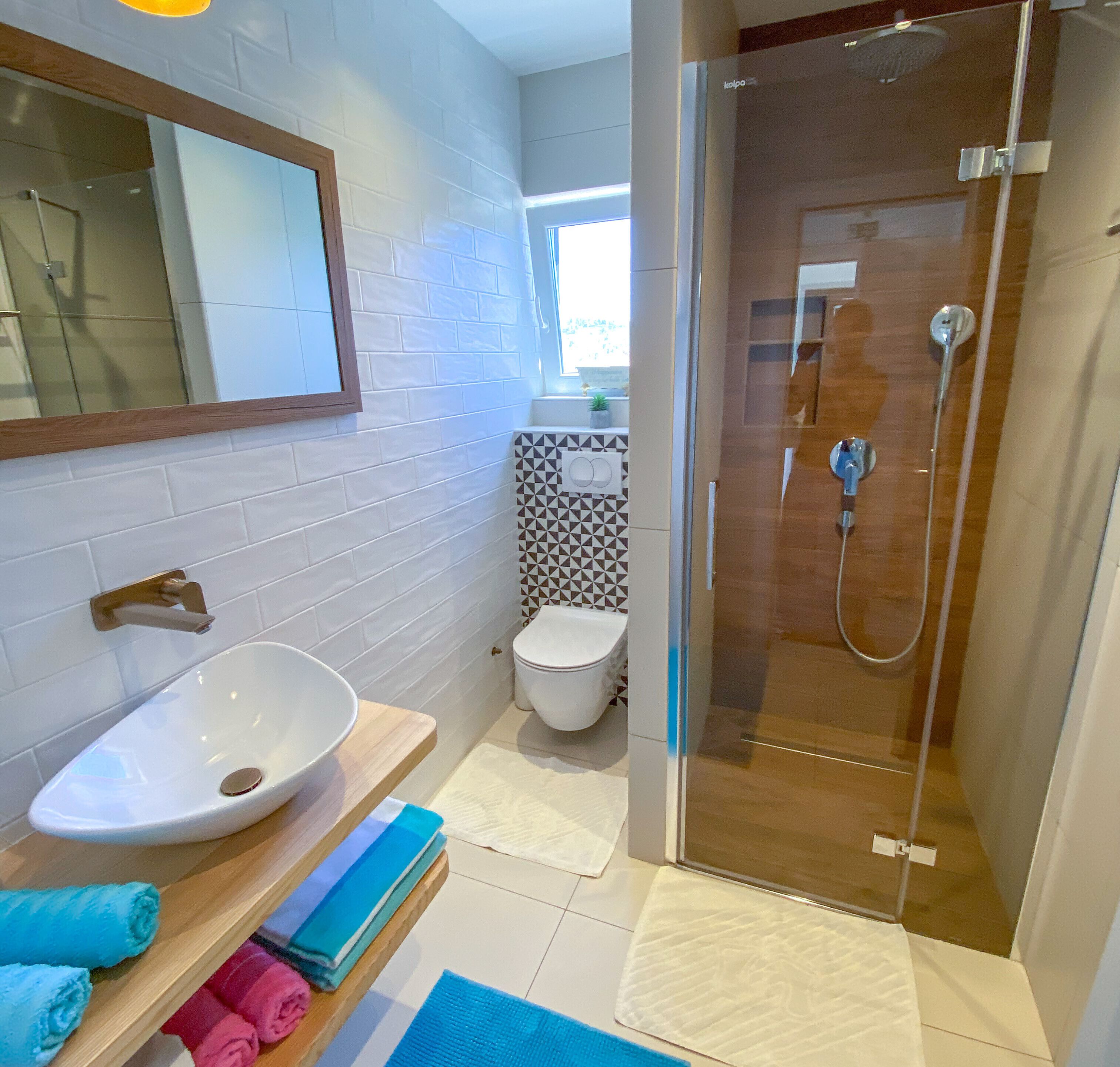 A modern bathroom with a white sink, a glass shower enclosure, and a toilet.