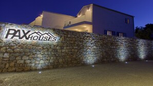 A stone wall with a sign for "PAXHOUSES" and a modern building with a balcony. - Pax house with private pool 2 (Krk)