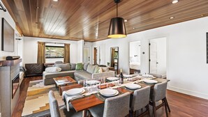 Un salon moderne avec un coin repas, un plafond en bois et une cheminée.